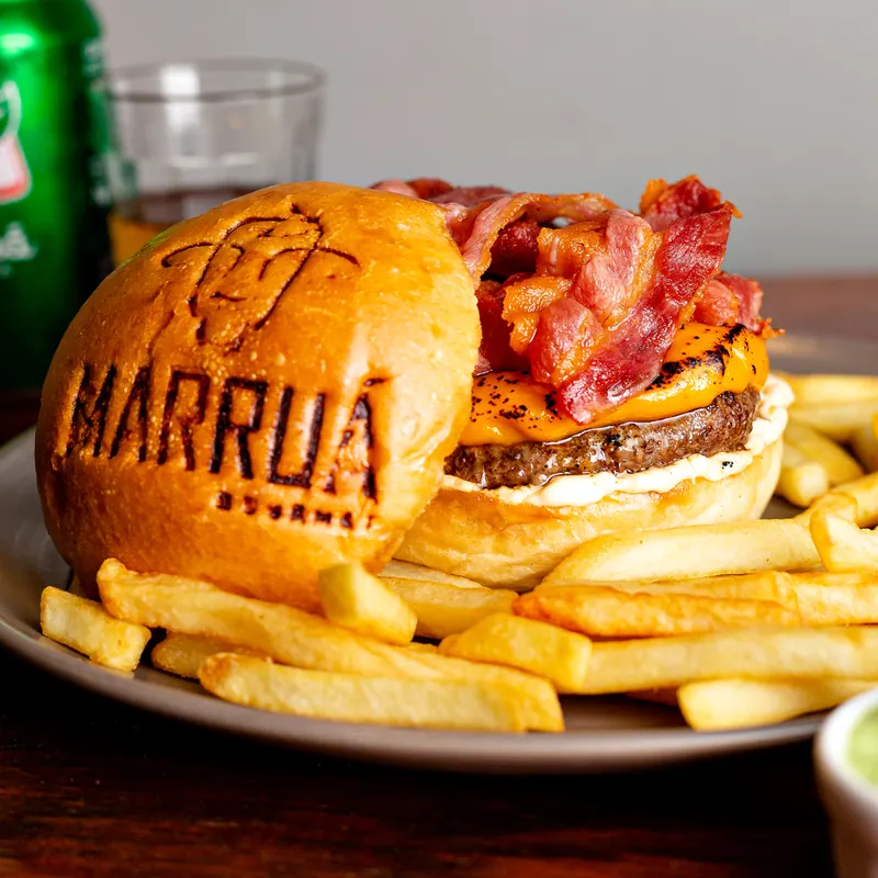 Hambúrguer com o nome Marruá gravado no pão, bacon crocante e cheddar, com batatas fritas