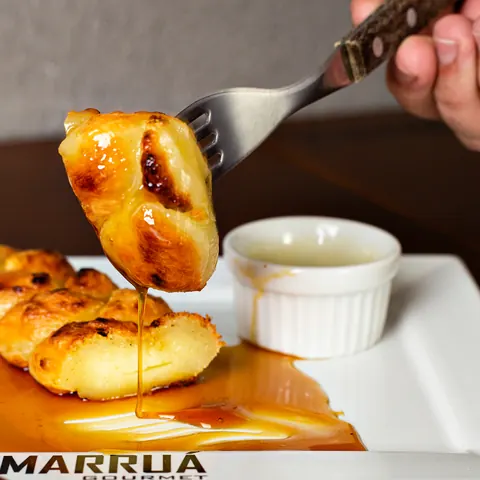 Queijo grelhado na brasa servido com melado escorrendo