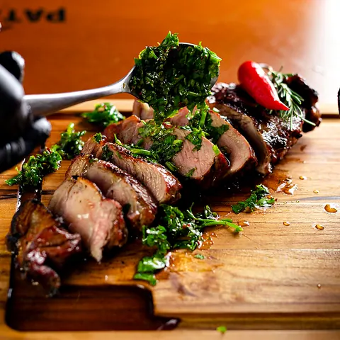 Steak fatiado ao ponto coberto com chimichurri